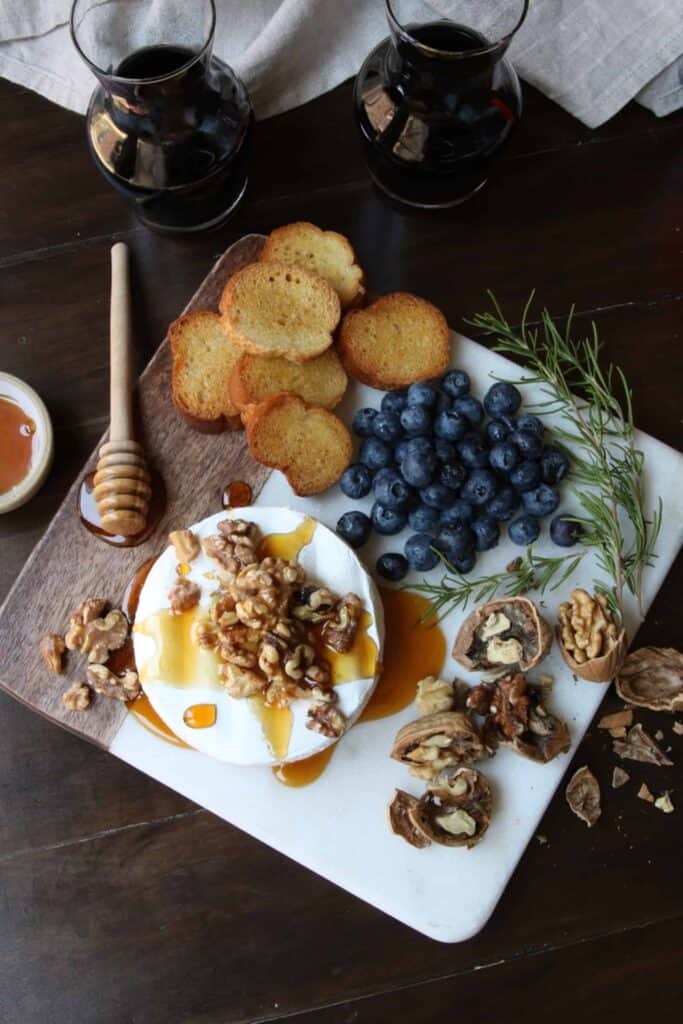 Warm Cheese Board on a marble platter with walnuts, blueberries and bread